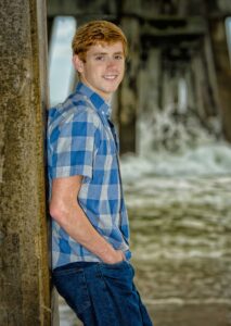 High school student posing for his senior photo on the beach