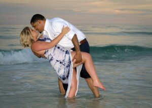 Couple in the water after a surprise proposal on the beach.