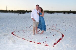 Couple standing on the beach in a heart made form rose petals
