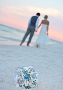 Bride and groom walking towards sunset with bouquet in the foreground