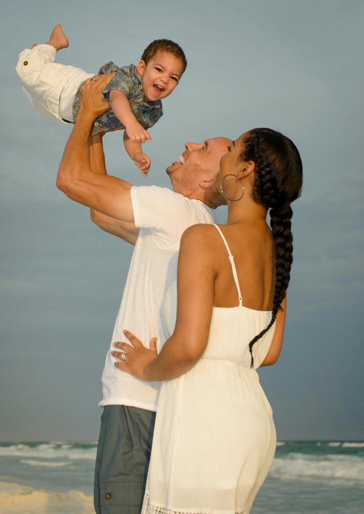 Couple with child on beach smiling for a beach portrait