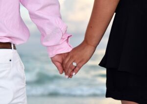 Closeup of couple holding hands showing new engagement ring