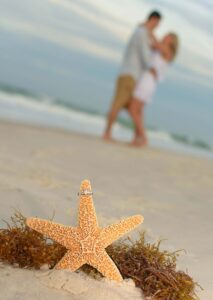 Ring on starfish, couple in the background
