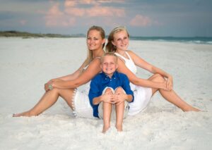 Siblings sitting on sand.