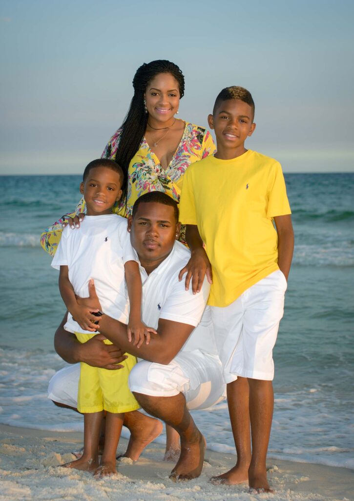 Sunset photo of family standing near water in Destin, FL.