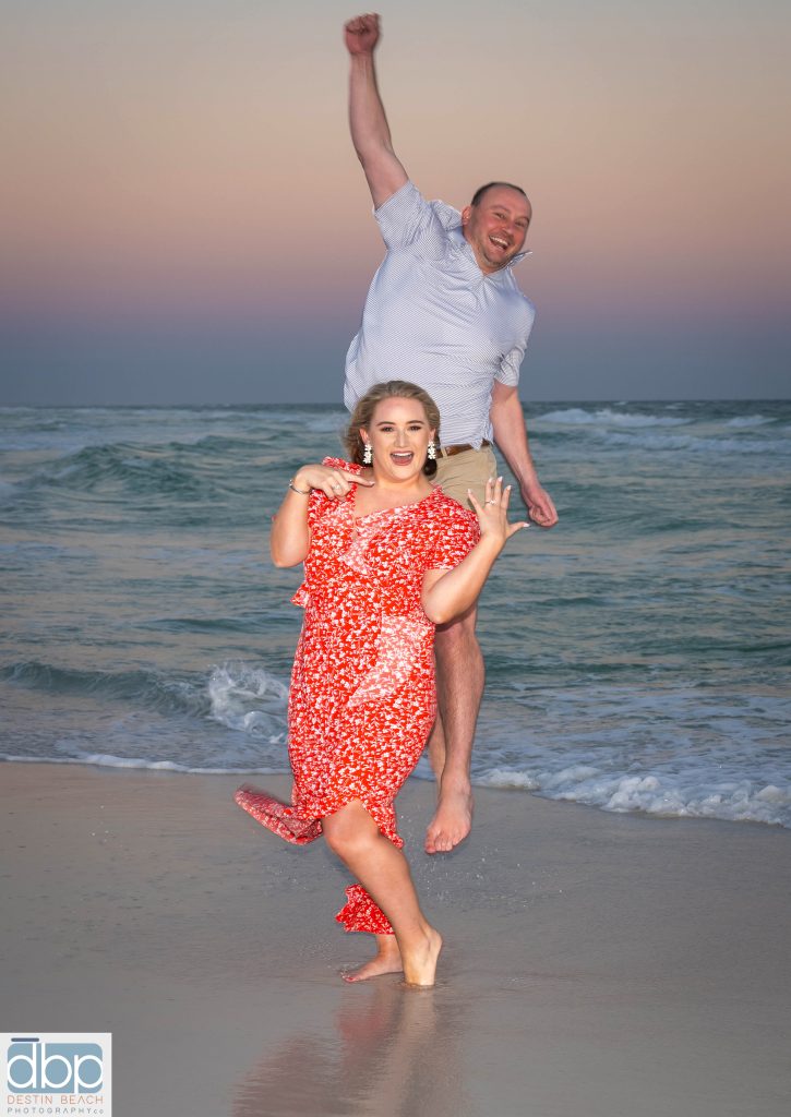 Newly engaged couple on beach celebrating after Surprise Proposal.